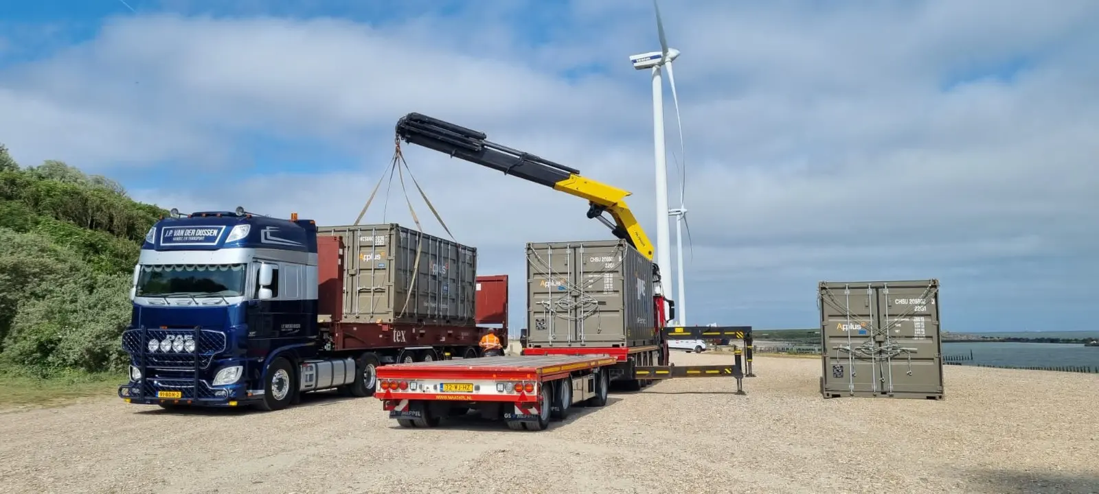 Project cargo: containers craned onto a trailer on a coastal site